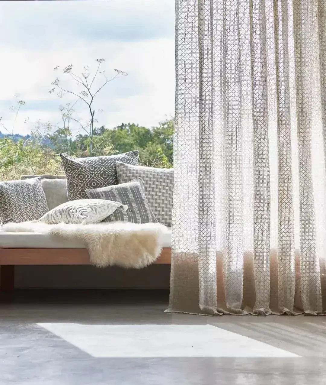 Layered curtains and a fitted upholstered window seat in a residential interior